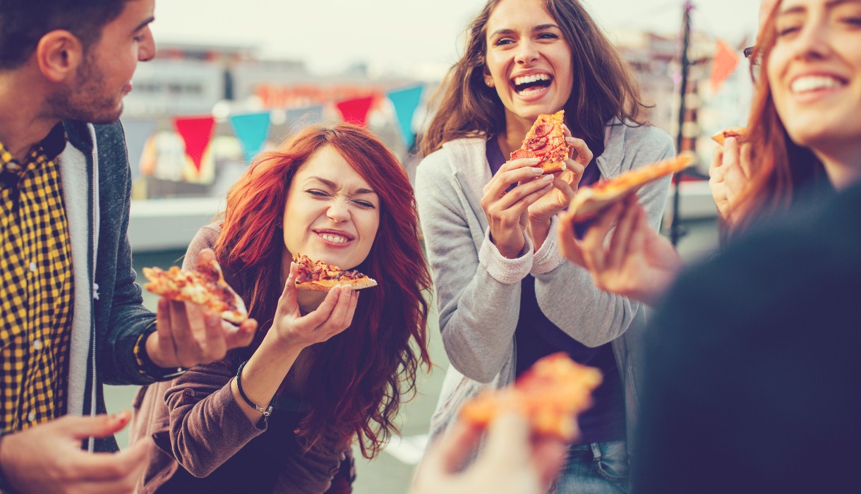 Best Places for Pizza in Hendersonville, NC - Young people eating pizza at party - image by pixelfit from Getty Images Signature