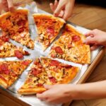 Pizza Joints Near Blowing Rock NC Eating Pizza. Group Of Friends Sharing Pizza. Image by puhhha from Getty Images Pro